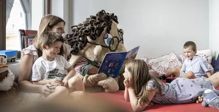 Children listen to a person in a large mascot costume reading a book