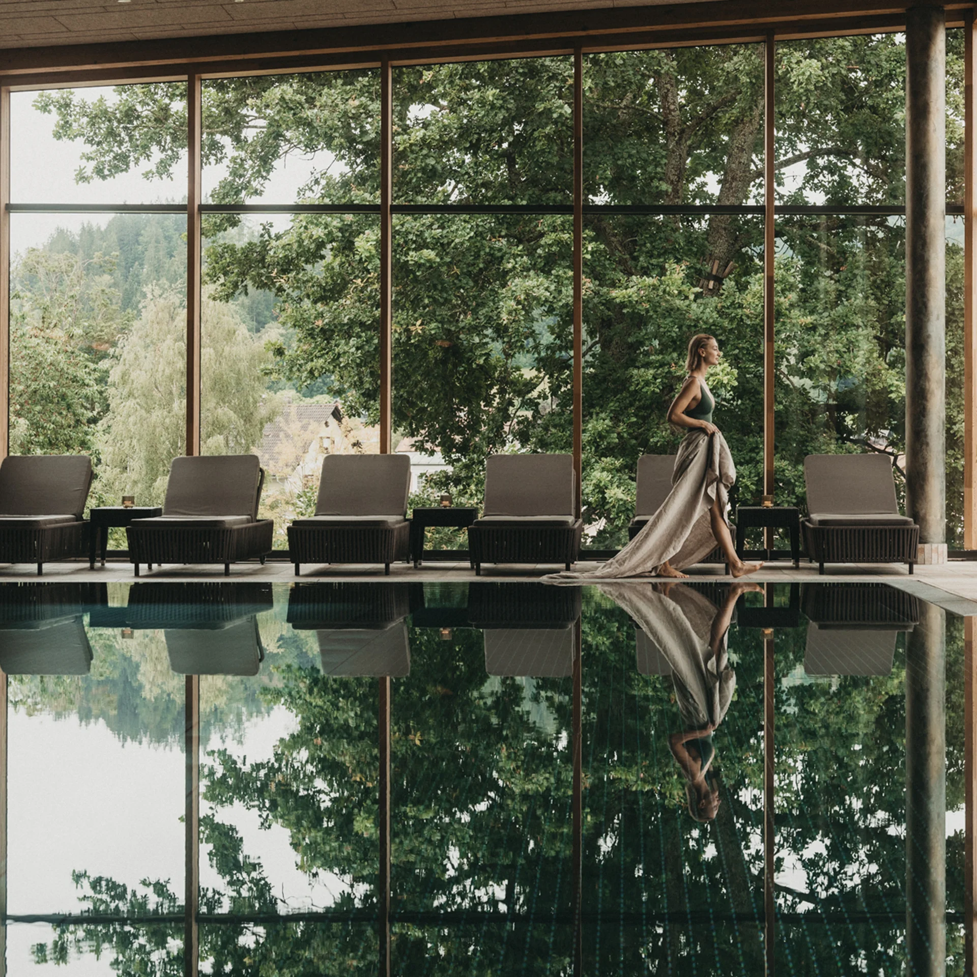 Il posto dove gli ospiti tornano: una seconda casa a Frauenau Donna in abito lungo accanto alla piscina coperta con vista sul verde