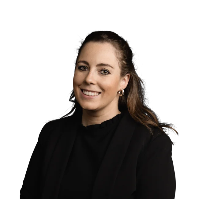 Porträt einer lächelnden Frau mit braunen Haaren und schwarzem Blazer vor weißem Hintergrund