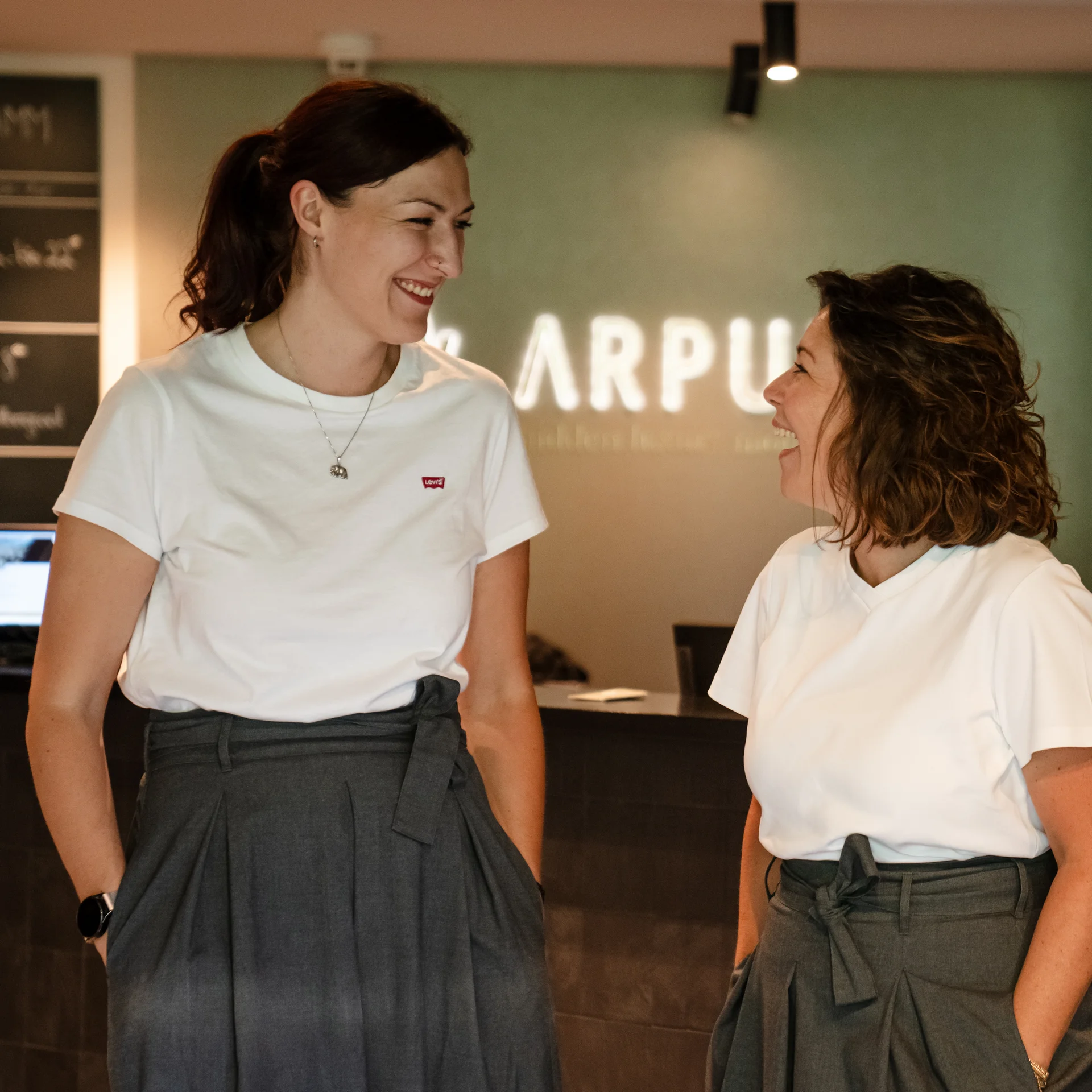 Zwei Frauen lachen zusammen in einem modernen Büro
