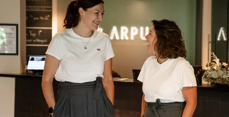 Two women laughing together in a modern office