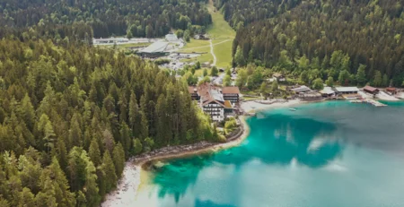 The best references for our hotel marketing Aerial view of a hotel by turquoise lake surrounded by forest and mountains