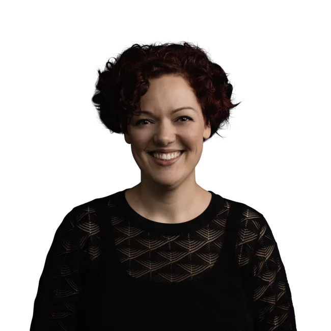 Victoria Morandell Ritratto di donna sorridente con capelli rossi ricci corti e maglia nera trasparente