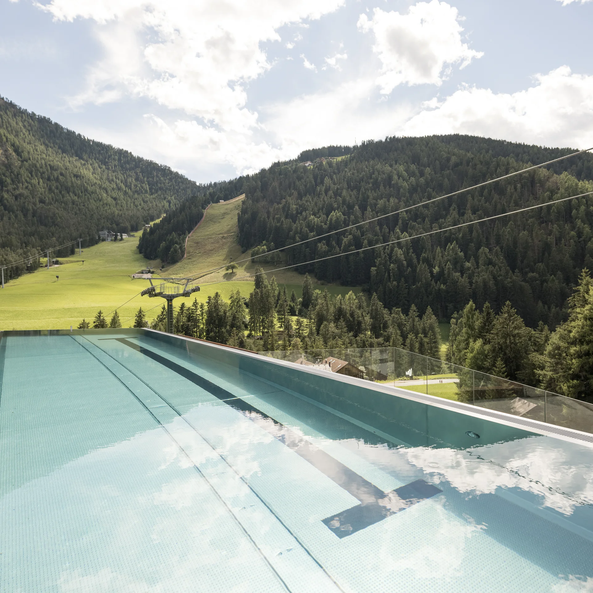 Infinity pool overlooking green forested mountains and blue sky
