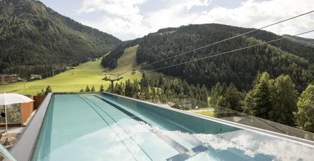 Infinity pool overlooking green forested mountains and blue sky