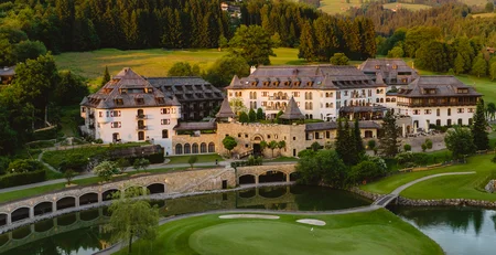 Luxushotel an einem Golfplatz mit Bergen und Wäldern im Hintergrund