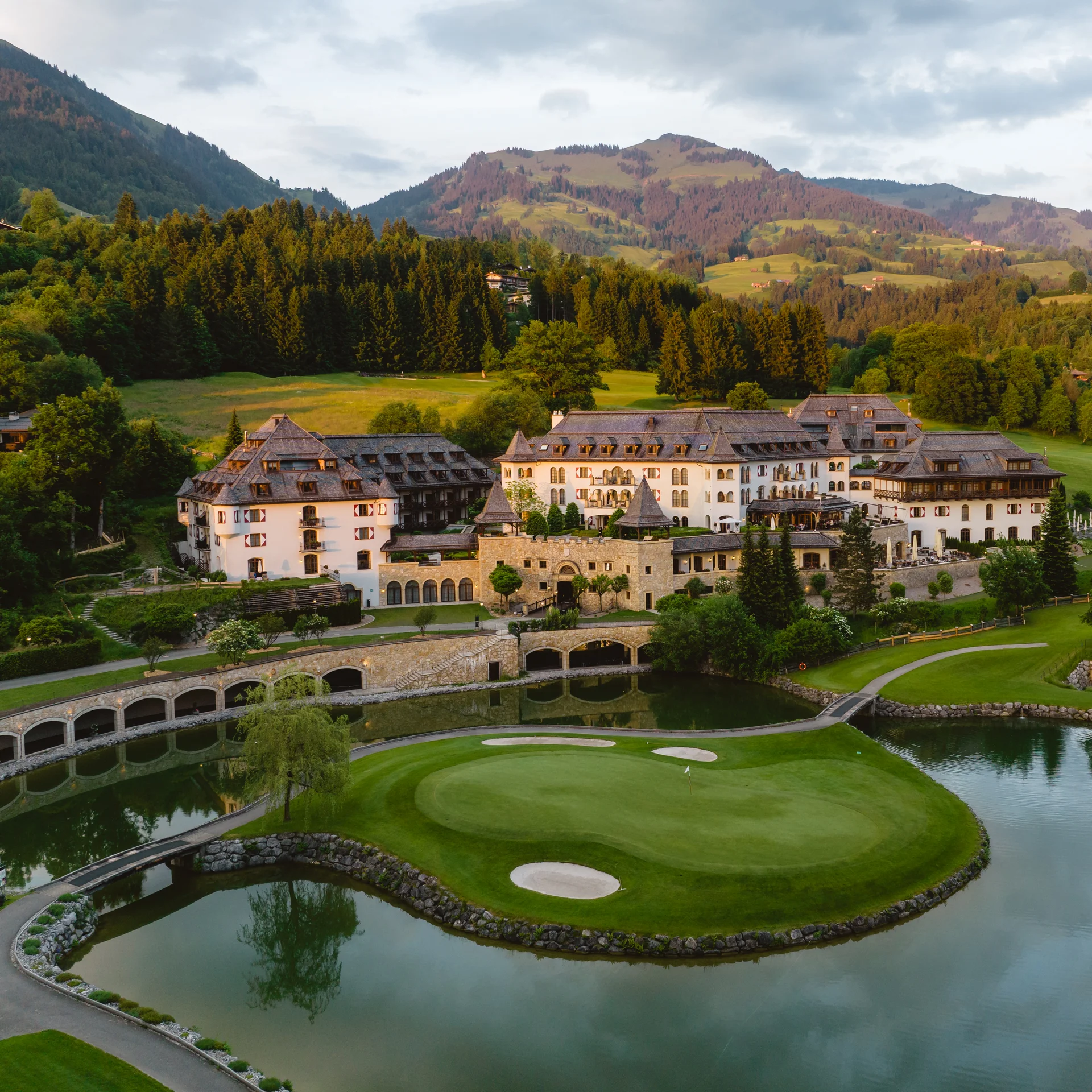Luxushotel an einem Golfplatz mit Bergen und Wäldern im Hintergrund