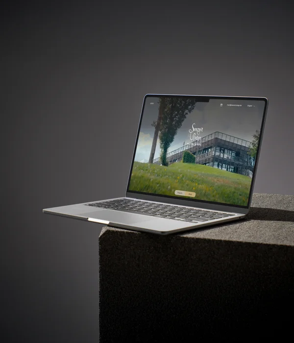 Laptop displaying Seezeit Lodge Hotel & Spa website with building on grassy hill and trees