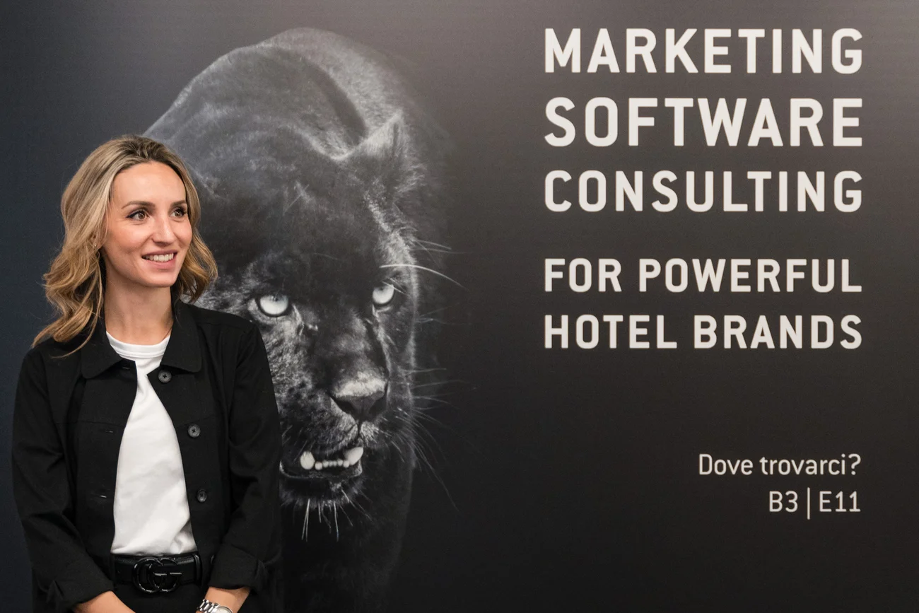Frau vor Wand mit Text zu Marketing-Software-Beratung für Hotelmarken