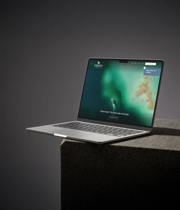 Laptop displaying hotel website on a dark pedestal