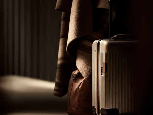 Reisekoffer und Ledertasche neben einer gehängten Jacke bei schwachem Licht