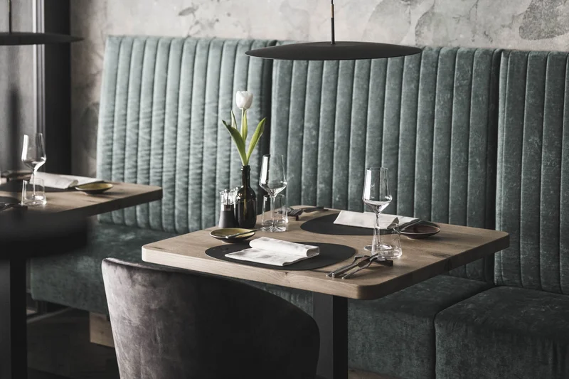 Marketing a 360° per un’esperienza a 360° Ristorante moderno con divano in velluto verde e tavolo apparecchiato