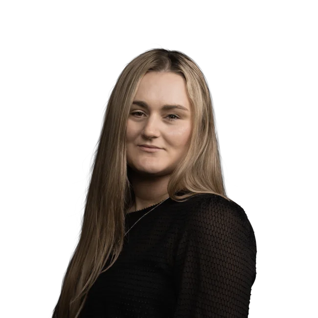 Porträt einer Frau mit langen blonden Haaren und schwarzem Oberteil vor weißem Hintergrund