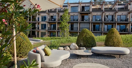 Modern outdoor seating area with furniture in front of wooden building in sunlight