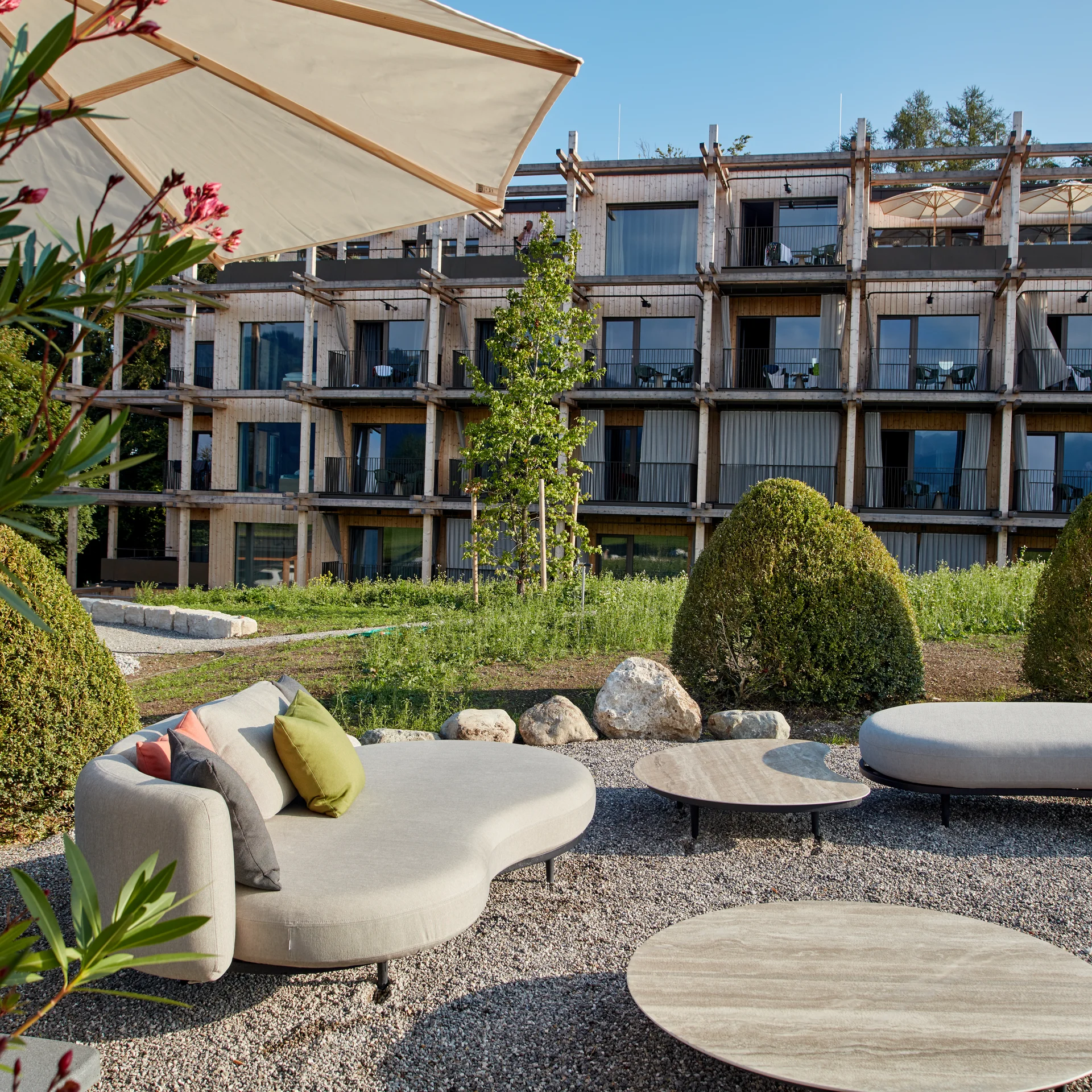 Moderner Außenbereich mit Sitzmöbeln vor einem Holzgebäude bei Sonnenschein