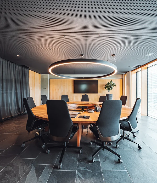 Modern conference room with round wooden table and black office chairs