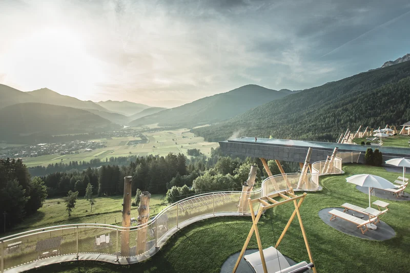 Luxuriöse Terrasse mit Schaukeln, Liegestühlen und Infinity-Pool in den Bergen