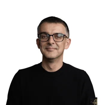 Porträt eines lächelnden Mannes mit schwarzem Pullover und Brille vor weißem Hintergrund