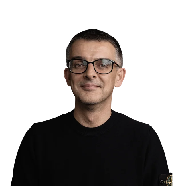 Porträt eines lächelnden Mannes mit schwarzem Pullover und Brille vor weißem Hintergrund