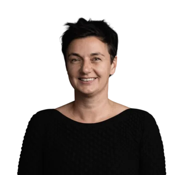 Bettina Conci | Senior Copywriter Corporate Brands Portrait einer lächelnden Frau mit kurzen schwarzen Haaren im schwarzen Pullover