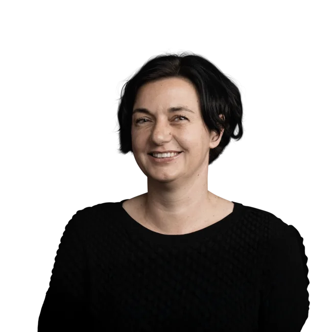 Portrait einer lächelnden Frau mit kurzen schwarzen Haaren im schwarzen Pullover