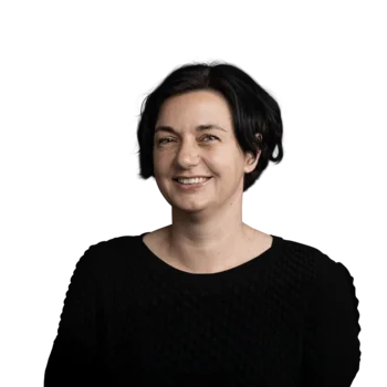 Portrait einer lächelnden Frau mit kurzen schwarzen Haaren im schwarzen Pullover