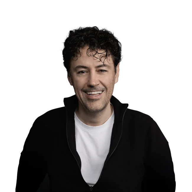 Porträt eines lächelnden Mannes mit lockigem Haar und schwarzem Oberteil