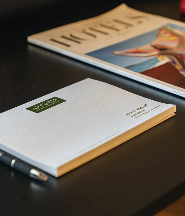 Notizblock und Stift auf schwarzem Tisch neben Magazin