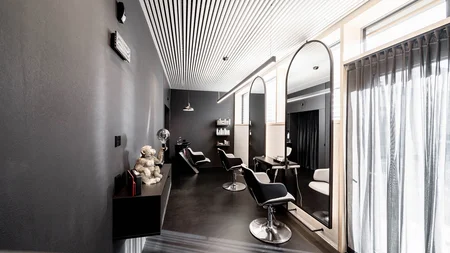 Modern hair salon with black furniture and large mirrors