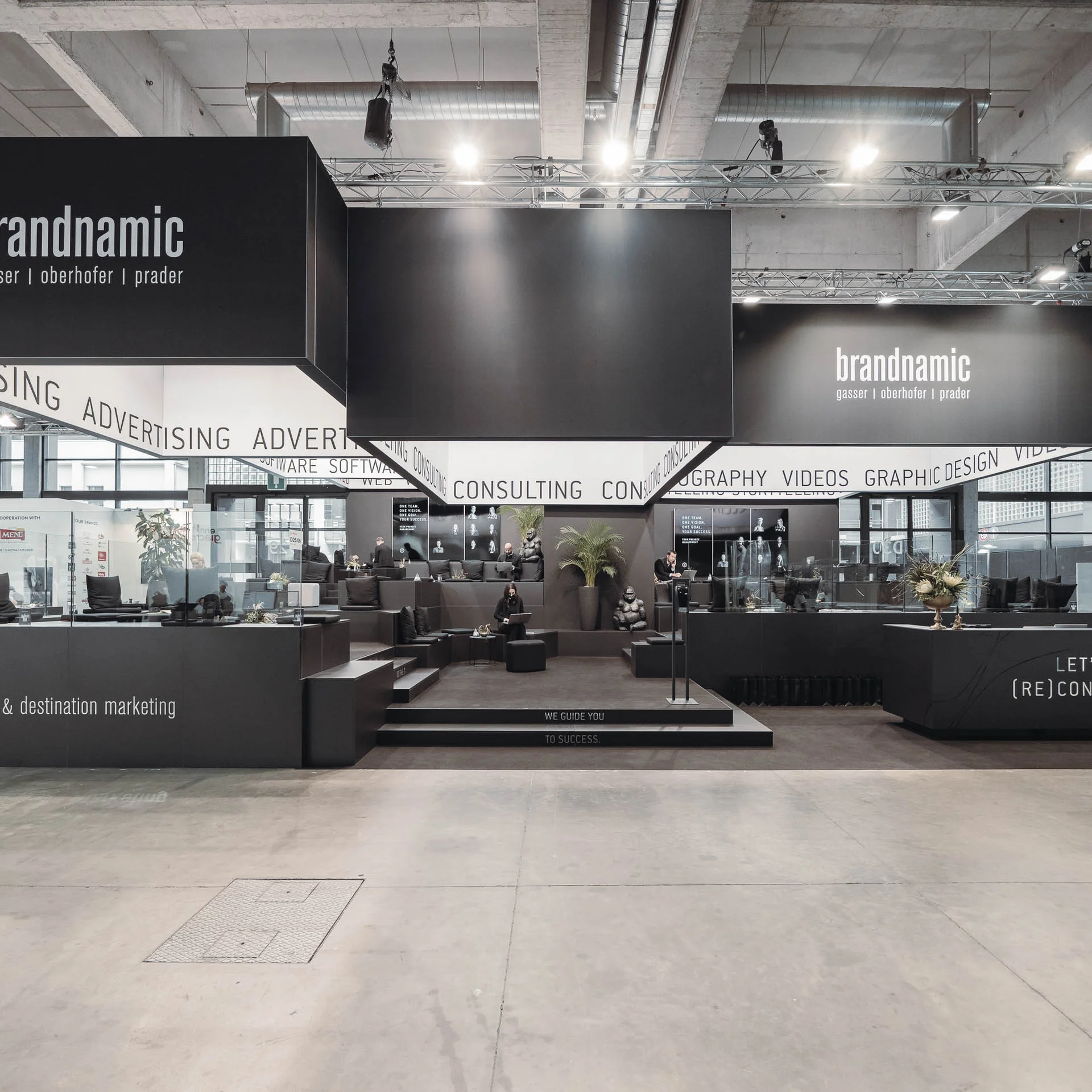 Moderner Messestand mit schwarzem Branding und Marketingthemen in einer Halle