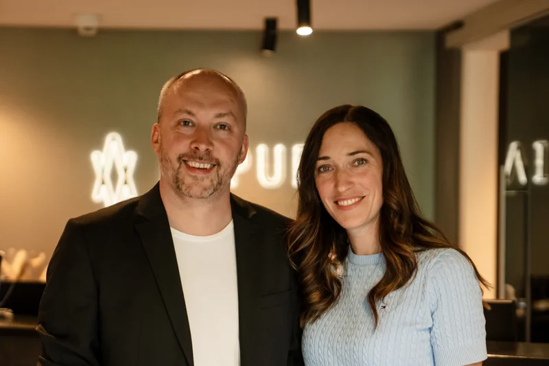 Lächelndes Paar steht vor Empfangstresen in moderner Umgebung