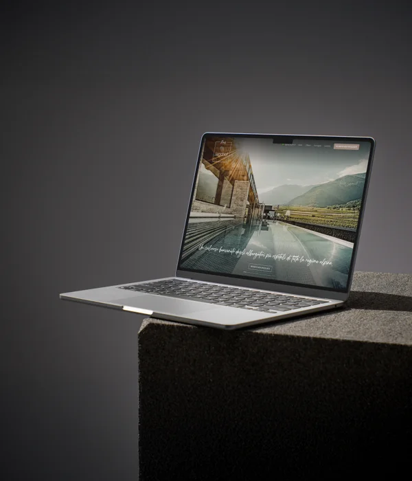 Due mondi, una firma Laptop con sito web di una struttura alberghiera tra montagne su un tavolo scuro