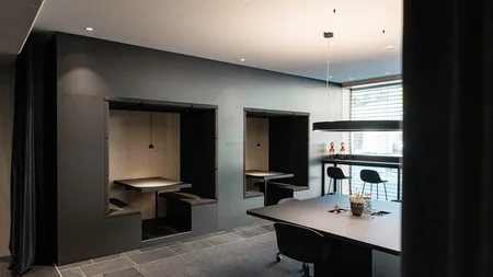 Modern meeting room with seating niches, table, and large windows