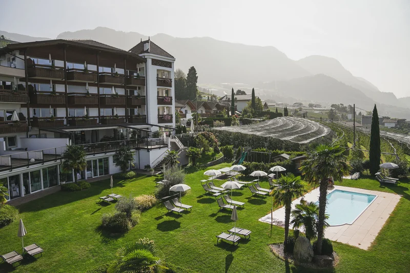 Kröll in Schenna: ein Haus für Momente in #echtzeit Hotel mit Garten, Pool und Liegestühlen vor Berglandschaft