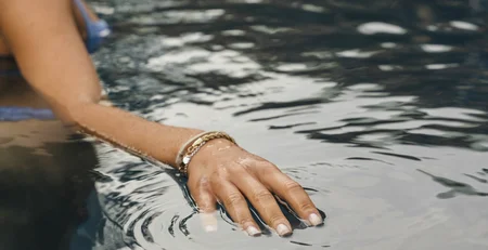 Woman touching water surface in a pool with gentle ripples