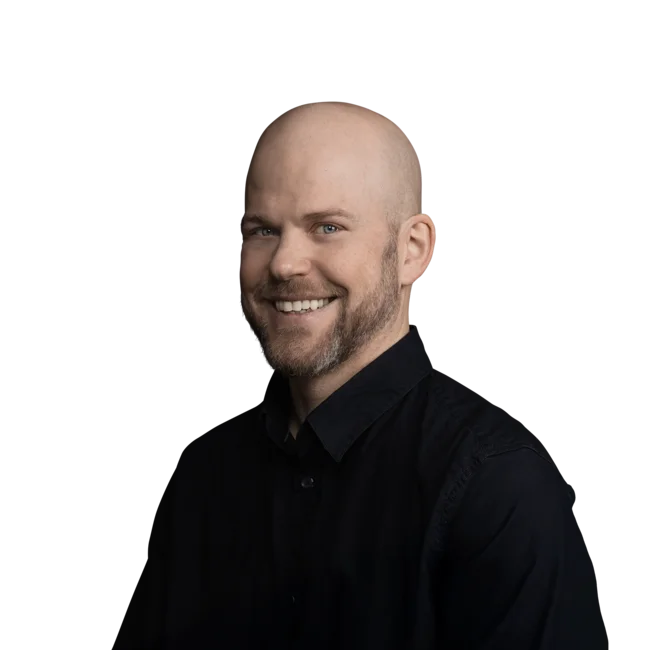 Lächelnder Mann mit Glatze und Bart in schwarzem Hemd vor weißem Hintergrund