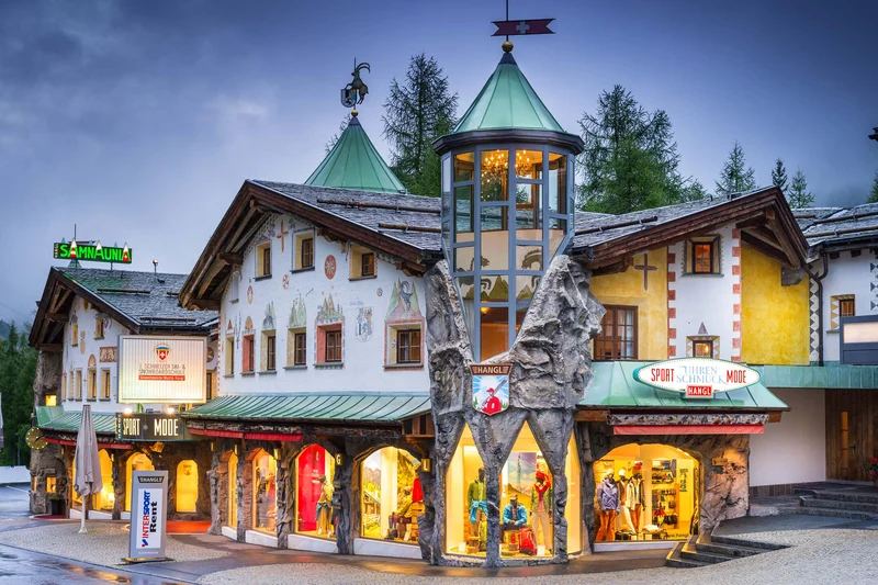 Beleuchtetes Chalet in Samnaun mit dekorativem Turm und Schaufenstern bei Dämmerung