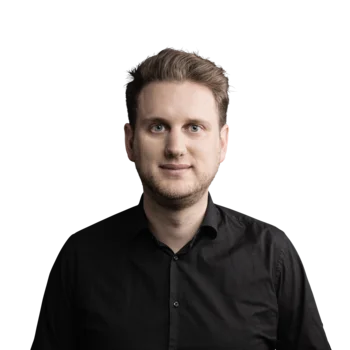 Junger Mann mit blondem Haar und schwarzem Hemd vor weißem Hintergrund