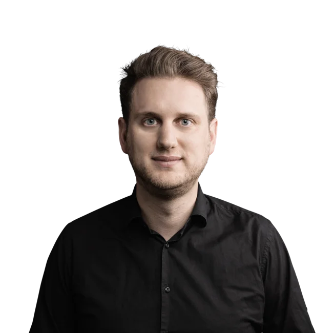 Thomas Stein Junger Mann mit blondem Haar und schwarzem Hemd vor weißem Hintergrund