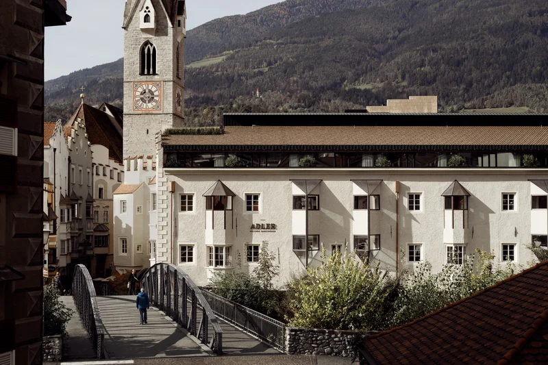 Marketing, das sich rundum richtig anfühlt. Historisches Gasthaus Adler und Kirche mit Uhr in einer Alpenstadt