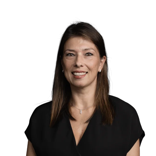 Frau mit braunen Haaren lächelt, schwarzes Oberteil und Halskette vor weißem Hintergrund