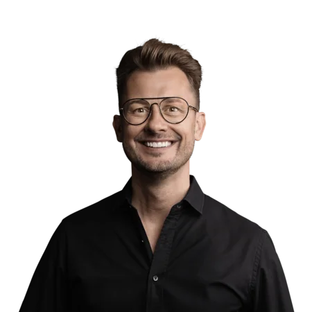 Mann mit Brille und schwarzem Hemd lächelt vor weißem Hintergrund