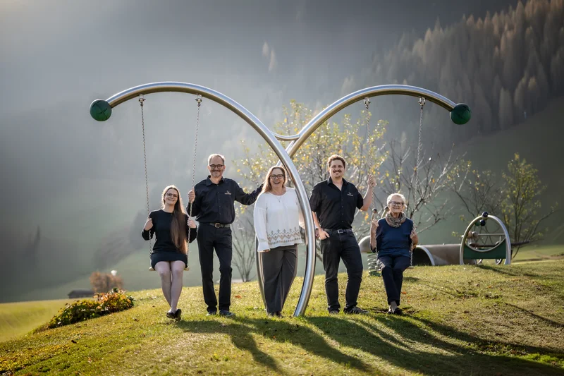 Fünf Personen vor einer Schaukel im Garten bei sonnigem Wetter