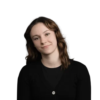 Sarah Indra | Customer Success Manager Junge Frau mit braunen lockigen Haaren, leichtes Lächeln, schwarzes Oberteil