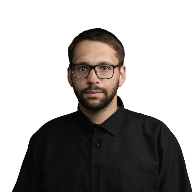Porträt eines Mannes mit Brille und schwarzem Hemd vor weißem Hintergrund