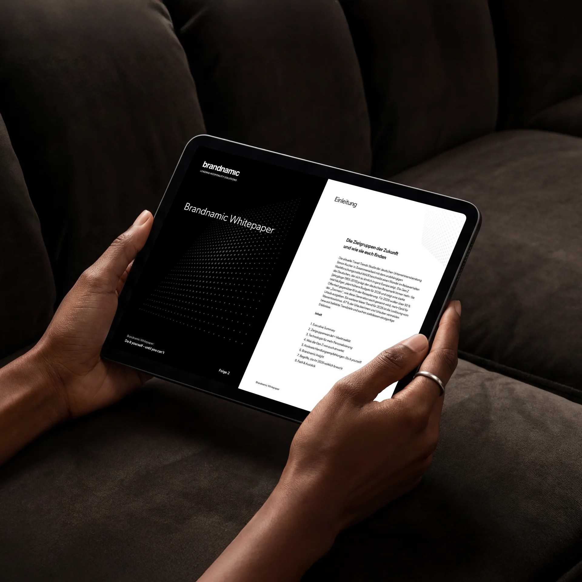 Person hält Tablet mit Brandnamic Whitepaper vor dunklem Hintergrund