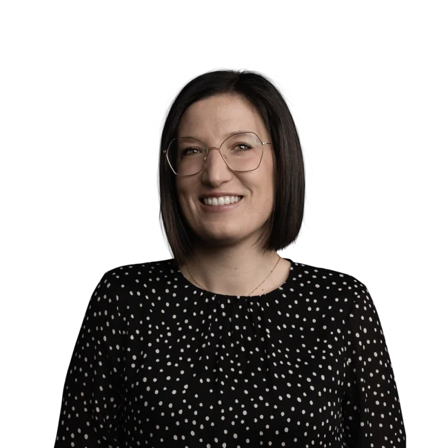 Frau mit schwarzer Brille und gepunktetem Oberteil lächelt