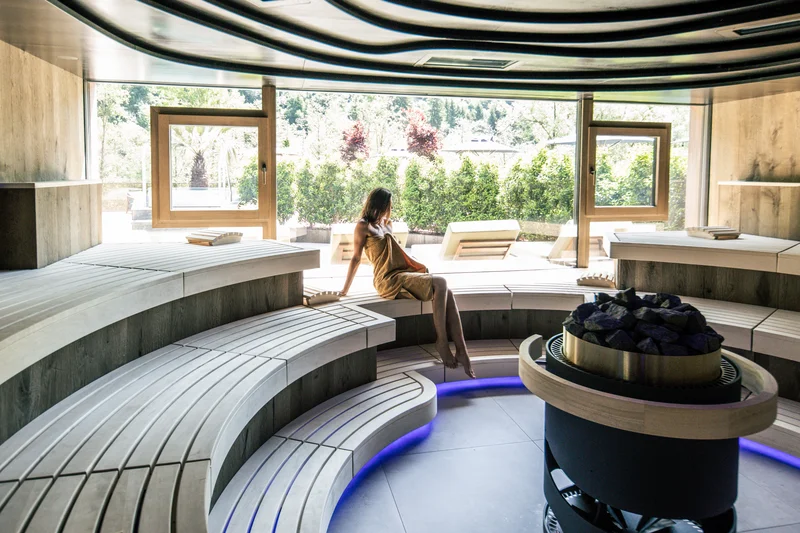 Moderne Sauna mit einer Person, Holzinterieur und großer Fensterfront