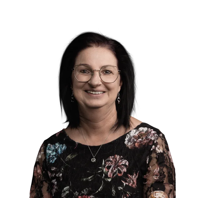 Porträt einer lächelnden Frau mit Brille und schwarzem, floralen Oberteil