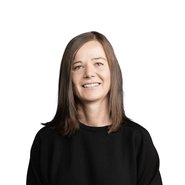 Lächelnde Frau mit schulterlangem braunem Haar und schwarzem Pullover vor weißem Hintergrund